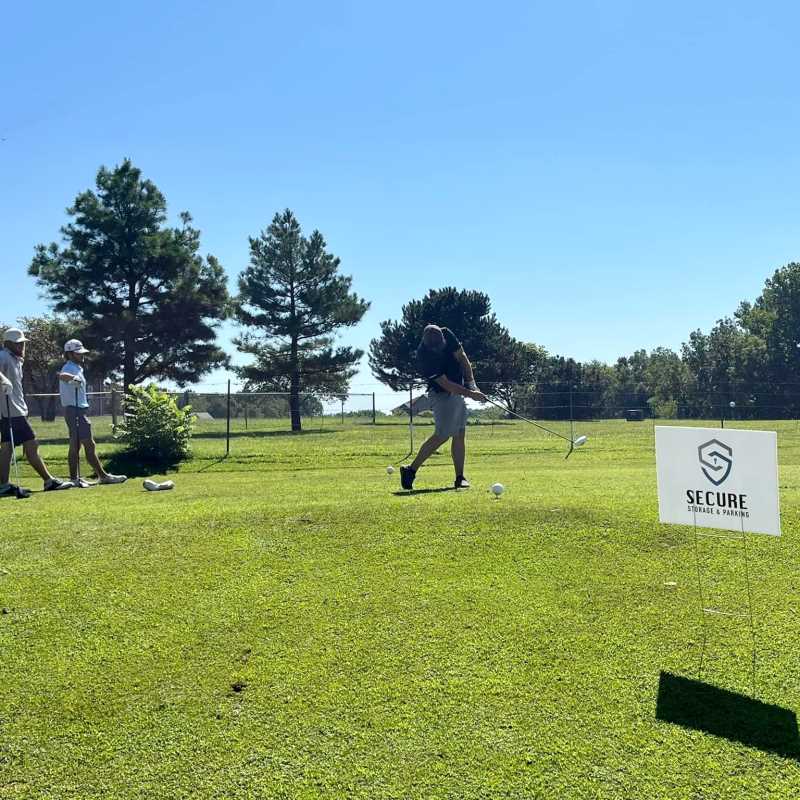 Golfer teeing off at the Drives for Downtown golf tournament