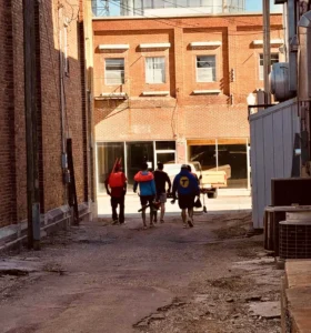 Volunteers walking through a downtown alley between historic brick buildings